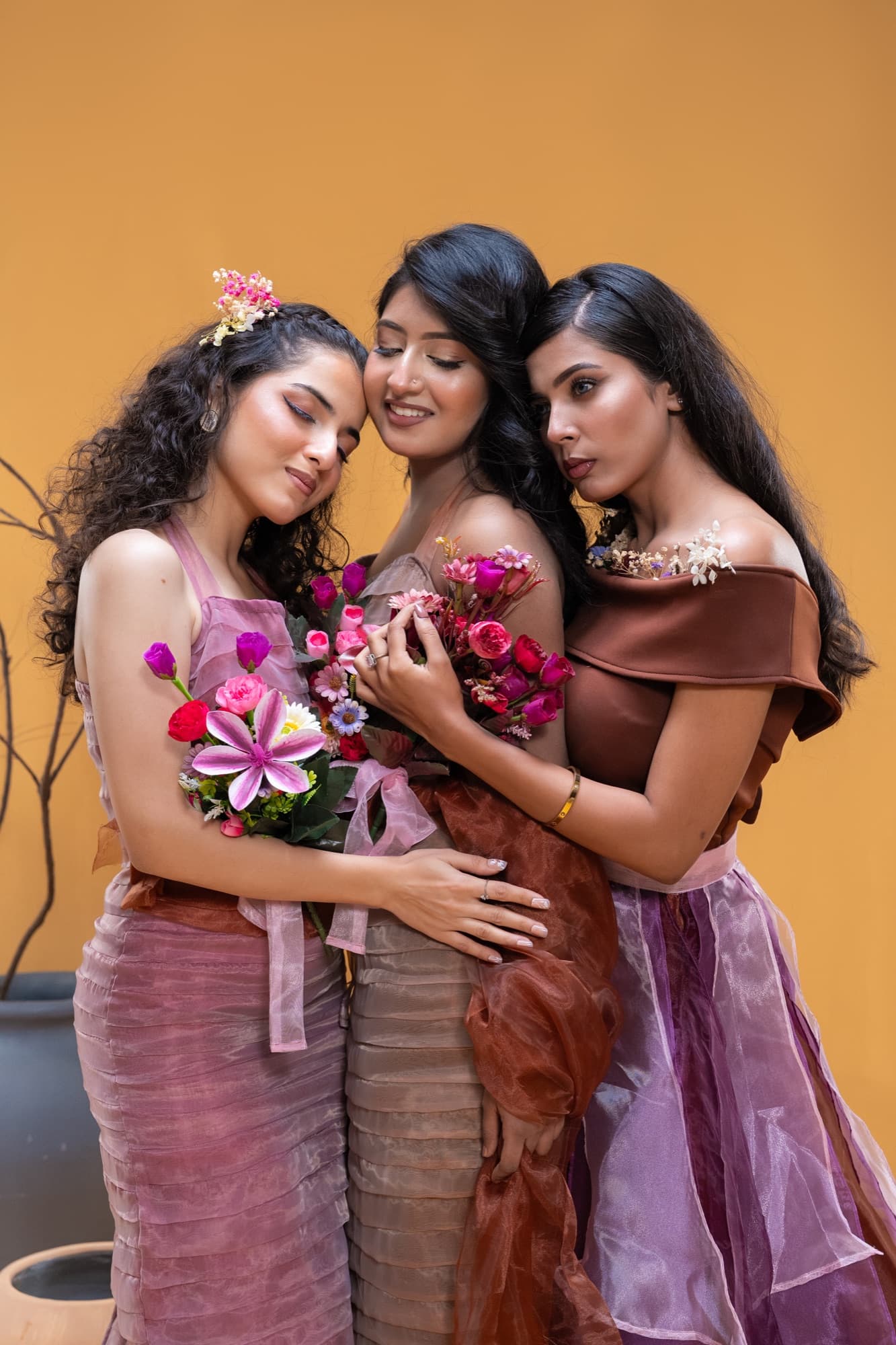 Petal Remains BUFT Graduation Couture Collection 2026 by Bangladeshi fashion designer Narin Juhi — three models in layered pink and violet organza holding bouquets against a mustard backdrop